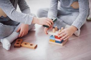 as crianças brincam com um designer de brinquedos no chão do quarto das crianças. duas crianças brincando com blocos coloridos. jogos educativos de jardim de infância foto