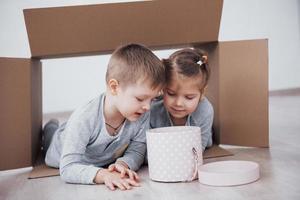 irmãozinho e irmãzinha brincando em caixas de papelão no berçário foto