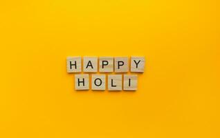 em marcha 8, holi é uma celebração do Primavera e brilhante cores dentro Índia, uma minimalista bandeira com a inscrição dentro de madeira cartas foto