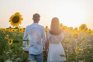 lindo casal se divertindo em campos de girassóis foto