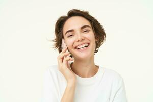 retrato do feliz, tagarela jovem mulher falando em Móvel telefone, usando Smartphone, chamando alguém, em pé sobre branco estúdio fundo foto