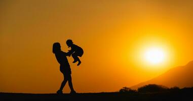 silhueta, feliz mãe e filha abraço lançar Alto em a campo gramado às pôr do sol dentro a tarde. amor família atividade relaxar conceito. foto