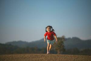 feliz bebê ásia menina sorridente. pequeno menina corrida e sorridente às pôr do sol feliz bebê menina sorridente. pequeno bebê corrida às pôr do sol. fofa bebê corrida às Parque infantil jardim. foto