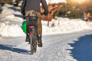 Ande de bicicleta em uma estrada com neve no inverno foto