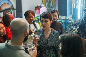 mulher segurando álcool beber vidro e a comemorar com amigos juntos dentro Boate. diverso pessoas desfrutando bebidas enquanto balada e festa em pista de dança às discoteca encontro foto