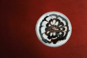 gelado mocha café café com leite arte chocolate flor forma espiral vidro em vermelho fundo foto