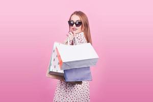 retrato de uma jovem mulher feliz e sorridente com sacolas de compras no fundo rosa foto