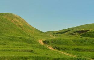 paisagem com um caminho pisado, passando por um maravilhoso terreno montanhoso verde. foto de belo espaço de relevo paisagístico com um caminho fino