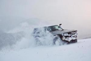 SUV viaja em montanhas de inverno, gerando risco de neve e gelo, derrapando foto
