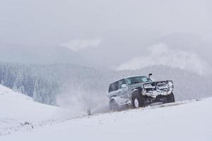 SUV viaja em montanhas de inverno, gerando risco de neve e gelo, derrapando foto