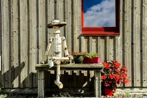 uma de madeira homem sentado em uma Banco lado de fora do uma casa foto