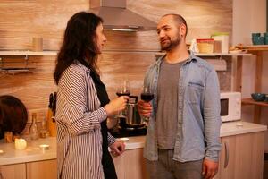 homem e mulher tendo Diversão durante encontro bebendo vinho. adulto casal tendo romântico encontro às lar, dentro a cozinha, conversando, sorridente, desfrutando a refeição dentro jantar sala. foto