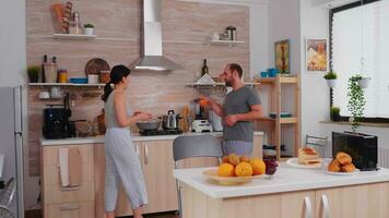 alegre casado casal preparando café da manhã e conversando. marido tendo uma conversação com esposa enquanto ela é preparando ovos para café da manhã. foto