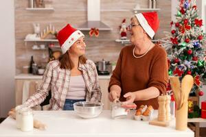 feliz família desfrutando inverno estação juntos preparando caseiro tradicional biscoitos massa dentro natal decorado culinária cozinha. neto cozinhando Pão de gengibre sobremesa a comemorar Natal feriado foto