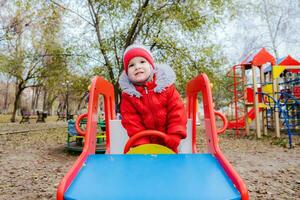 bebê sentado às a roda do uma crianças carro em a Parque infantil foto