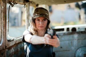 uma mulher com uma pistola dentro dela mão sofre militares Treinamento às uma Treinamento terra e aprende para atirar. foto