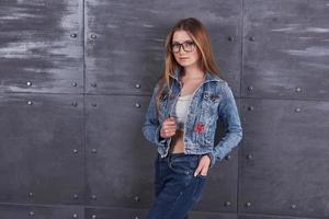 moda, roupas, conceito de pessoas. mulher jovem e atraente sexy com jaqueta jeans. garota está posando no estúdio