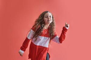jovem urbana dançando sobre fundo vermelho, adolescente elegante estilo hip-hop moderno foto