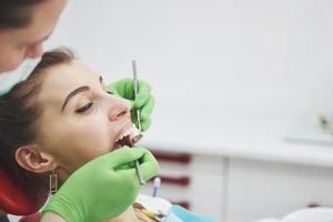 dentista curando uma paciente do sexo feminino na estomatologia. prevenção precoce e conceito de higiene bucal foto