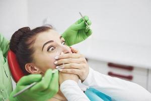 garota assustada no consultório do dentista cobriu a boca com as mãos. consultório odontológico com fobia de conceito