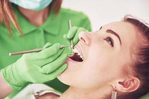dentista curando uma paciente do sexo feminino na estomatologia. prevenção precoce e conceito de higiene bucal foto