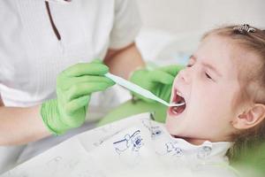 exame de dentes no consultório dentário. dentista examinando dentes de garotas na cadeira do dentista foto