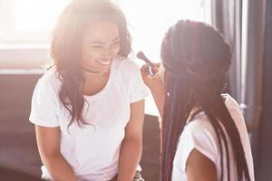 duas linda garota africana em pijamas sorrindo, sentado na cama em casa, acordaram de manhã em um dia ensolarado. foto