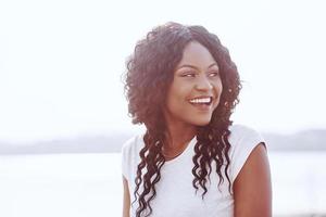 retrato de uma jovem negra sorridente com reflexo de luz solar foto