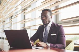 uma linda elegante empresária afro-americana de terno usa seu laptop enquanto trabalha
