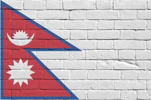 Nepal bandeira retratado dentro pintura cores em velho tijolo muro. texturizado bandeira em grande tijolo parede alvenaria fundo foto