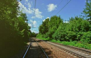 cenário verde de verão com trilhos de trem e céu azul foto