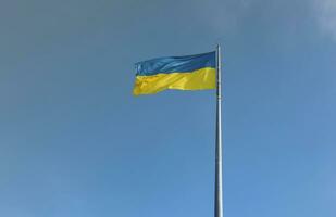 bandeira ucraniana isolada no céu azul com traçado de recorte. feche acenando a bandeira da ucrânia. símbolo de bandeira alta da ucrânia, país europeu foto