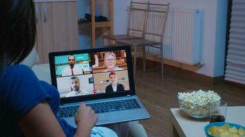 senhora participando às webinar sentado em sofá. controlo remoto trabalhador tendo conectados reunião, vídeo conferência consultando com colegas em Video chamada e Webcam bate-papo trabalhando dentro frente do computador portátil foto