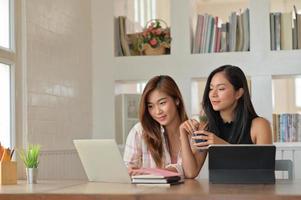 retrato de duas jovens em busca de informações em um laptop para fazer compras de forma feliz. foto