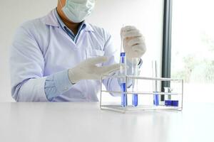 Ciência Inovativa masculino médico ou científico laboratório investigador executa testes com azul líquido dentro laboratório. equipamento Ciência experimentos tecnologia coronavírus covid-19 vacina pesquisa foto