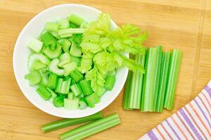 fresco picado salsão fatias dentro branco tigela com salsão Gravetos em bambu corte borda. vegano e vegetariano cultura. cru Comida. saudável dieta com negativo caloria conteúdo foto