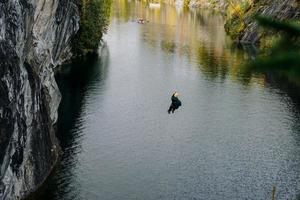 um homem pulando de uma bungee jump sobre um desfiladeiro no parque da montanha ruskeala foto