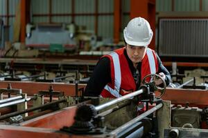 ásia industrial trabalhador é verificação a configuração valor do metal Folha lista formando máquina dentro cobertura fábrica para segurança indústria construção conceito foto