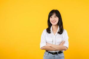 jovem empresária. retrato ásia mulher feliz sorridente, posando confiante, Cruz braços em peito, em pé contra amarelo estúdio fundo. inteligente jovem empreendedor publicidade produtos e Serviços. foto