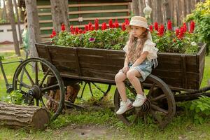 chateado pré-adolescente menina sentado em roda do vintage de madeira carrinho decorado Como canteiro de flores foto