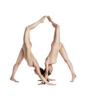 dois flexível meninas ginastas dentro bege collants realizando complexo elementos do ginástica usando apoiar, posando isolado em branco fundo. fechar-se. foto