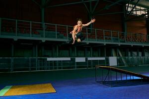 a jovem mulher executa uma truque. pular. interior Treinamento foto