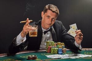 bonito emocional homem é jogando pôquer sentado às a mesa dentro cassino contra uma branco Holofote. foto