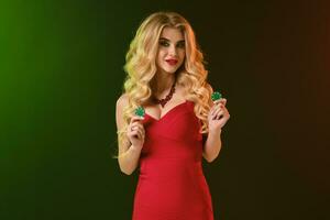 Loiras mulher dentro vermelho apropriado vestir e colar. ela sorridente, mostrando dois verde salgadinhos, posando em colorida fundo. pôquer, casino. fechar-se foto