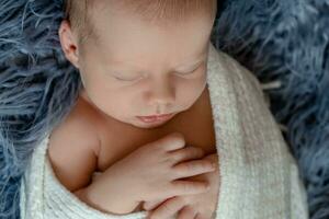 recém-nascido bebê Garoto dentro cama. Novo nascermos criança dormindo debaixo uma branco tricotado cobertor. crianças dormir. fechar-se foto