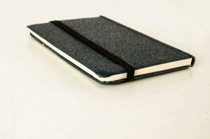 uma caderno com uma Preto cobrir sentado em uma branco superfície foto