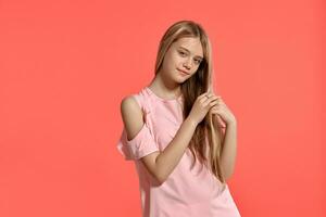 estúdio retrato do uma lindo menina Loiras adolescente dentro uma rosado camiseta posando em Rosa fundo. foto