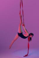 lindo menina dentro uma Preto roupa de banho é realizando a acrobático elementos dentro estúdio. foto