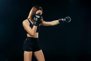 Atlético mulher dentro boxe luvas é praticando karatê dentro estúdio. foto