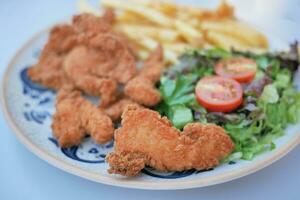 frito frango filetes servido com salada e francês fritas foto